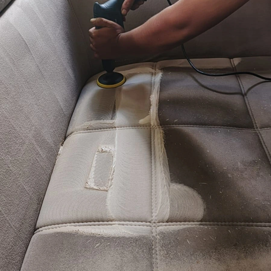 Sofa kain abu-abu yang kotor sedang dibersihkan teknisi Rawatin, tampak kontras bagian bersih dan kotor