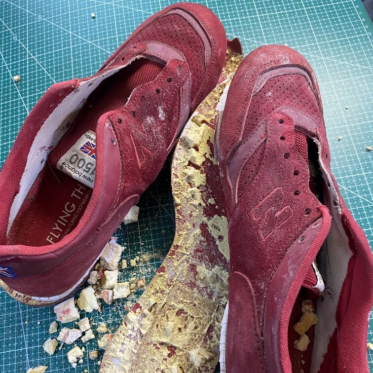 Sepatu New Balance merah dengan sol yang lepas dan hancur sebelum direparasi di Rawatin